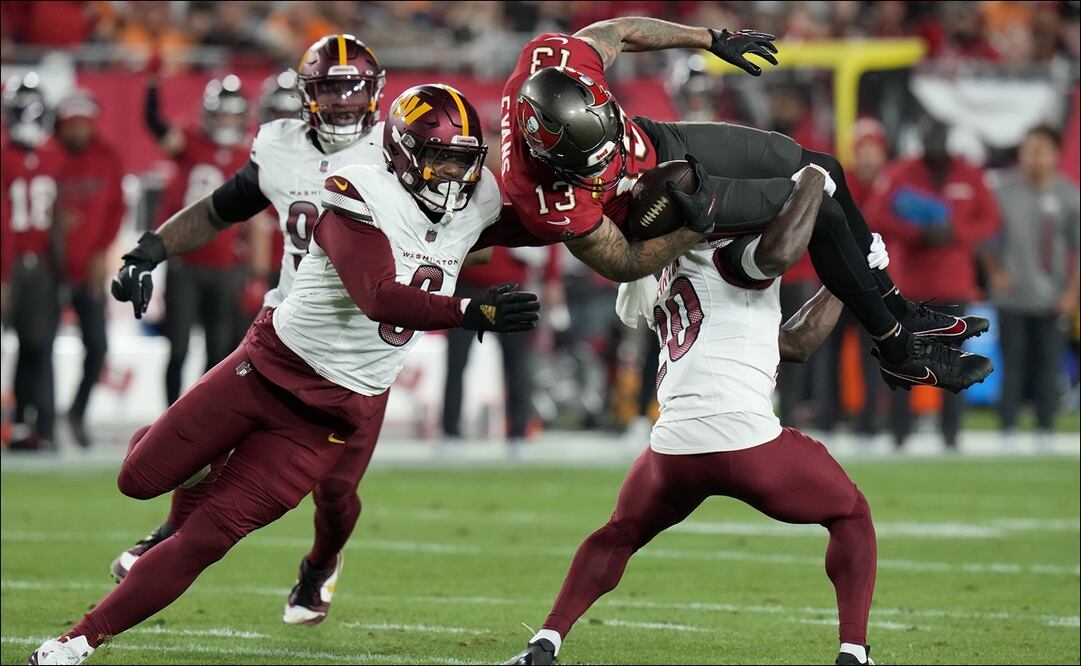 El receptor de los Buccaneers, Mike Evans (13), es tacleado por el safety Quan Martin y el linebacker Dante Fowler Jr. en el duelo de Comodines ante los Commanders. FOTO: AP