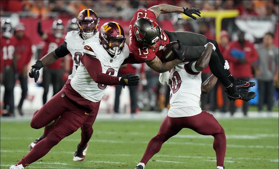 El receptor de los Buccaneers, Mike Evans (13), es tacleado por el safety Quan Martin y el linebacker Dante Fowler Jr. en el duelo de Comodines ante los Commanders. FOTO: AP