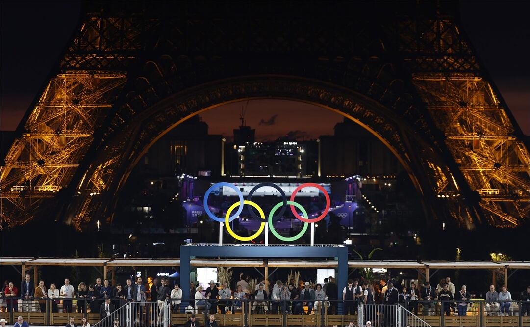 Los aros olímpicos se ubican al pie de la Torre Eiffel en medio de la noche parisina. FOTO: AFP