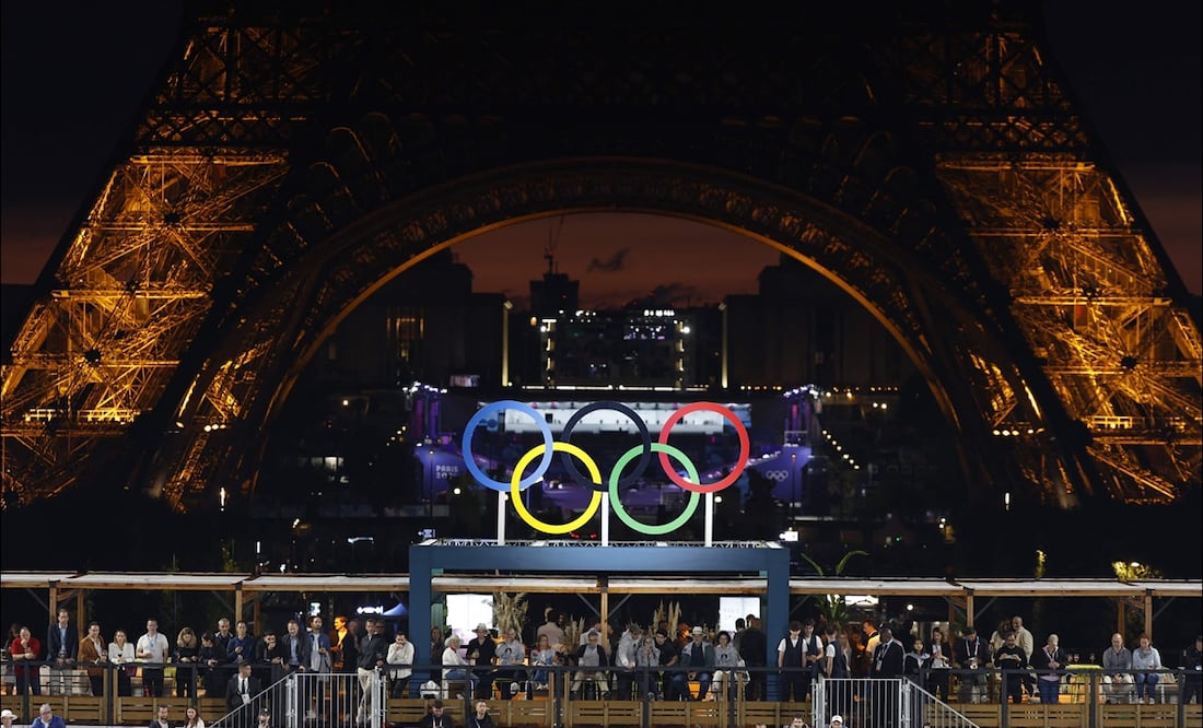 Los aros olímpicos se ubican al pie de la Torre Eiffel en medio de la noche parisina. FOTO: AFP