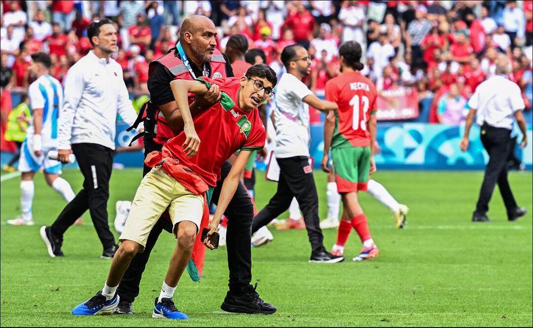 Un elemento de seguridad sujeta a un aficionado que invadió el campo en el partido Argentina vs Marruecos. FOTO: AFP
