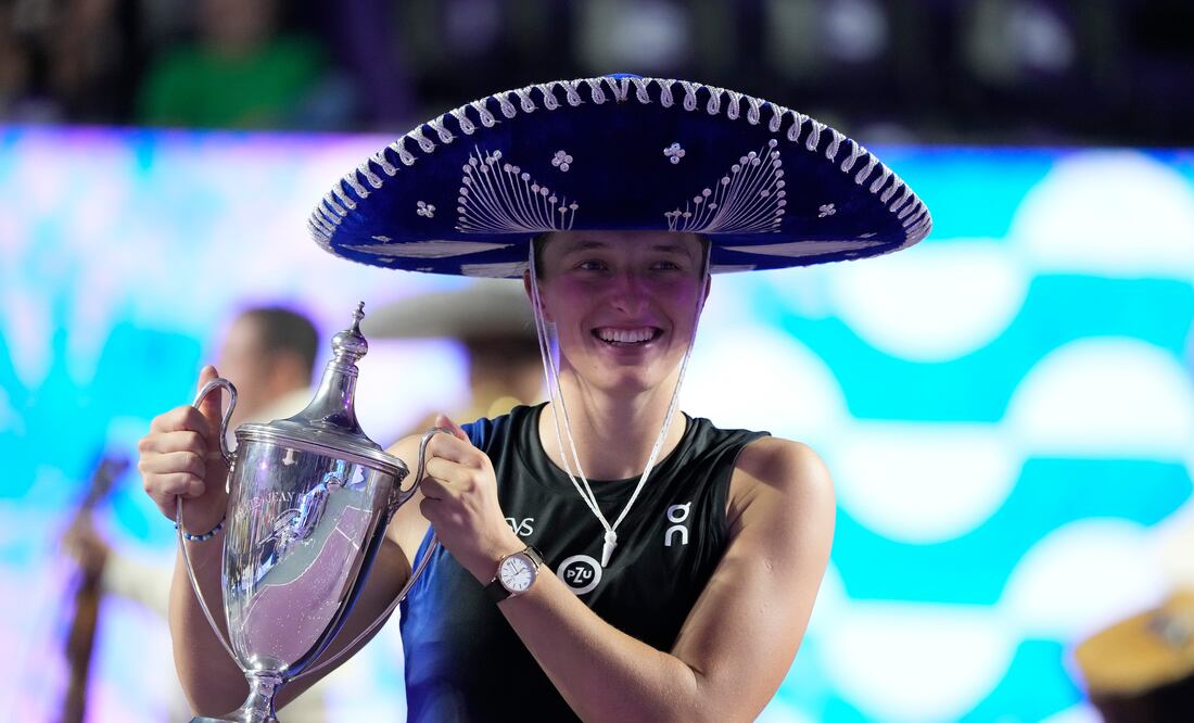 Iga Swiatek, of Poland, holds her trophy after her victory over Jessica Pegula, of the United States, in the women's singles final of the WTA Finals tennis championships, in Cancun, Mexico, Monday, Nov. 6, 2023. (AP Photo/Fernando Llano)