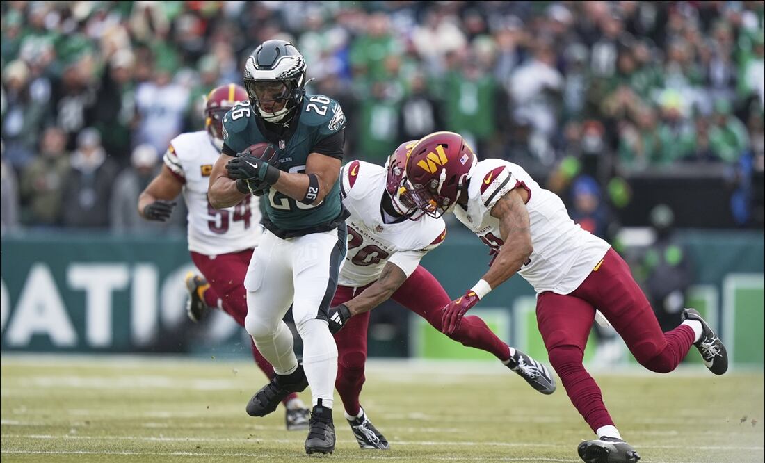 El corredor Saquon Barkley (26) de los Eagles supera a los defensivos de los Commanders, Quan Martin (20) y Jeremy Chinn para anotar un touchdown. FOTO: AP